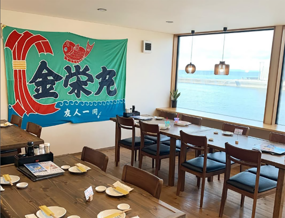 テーブルが並ぶ店内と窓から見える海の景色