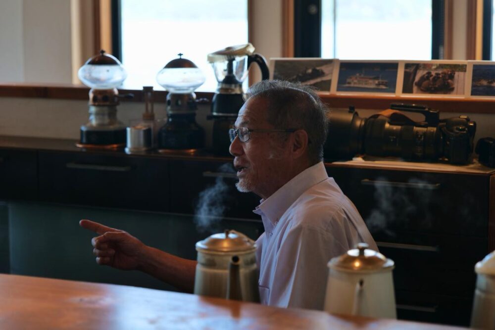 二郎さんの背後には、愛用のカメラと写真たち