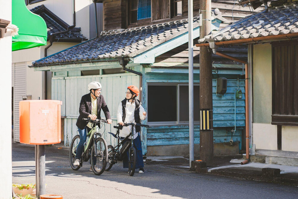 木造建築が連なる土佐市の町並みとE-BIKEを利用する二人