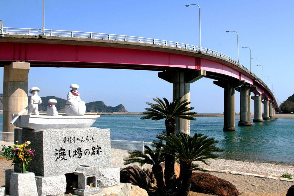 宇佐大橋の下にある「渡し場の跡」の石碑と遍路姿の石像
