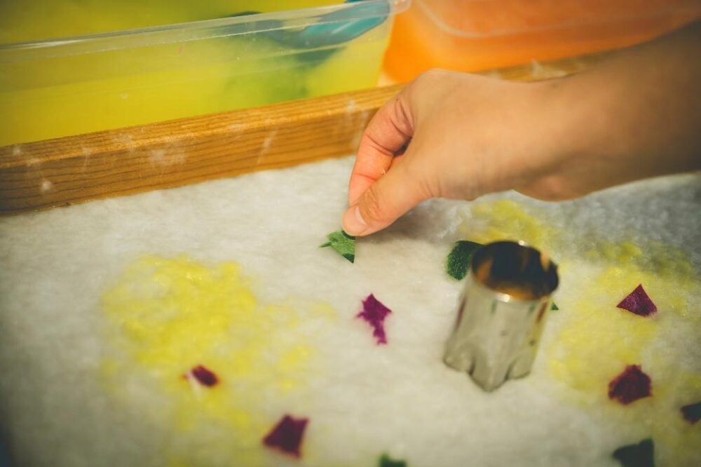 紙漉き体験で色付き和紙を飾り付ける様子