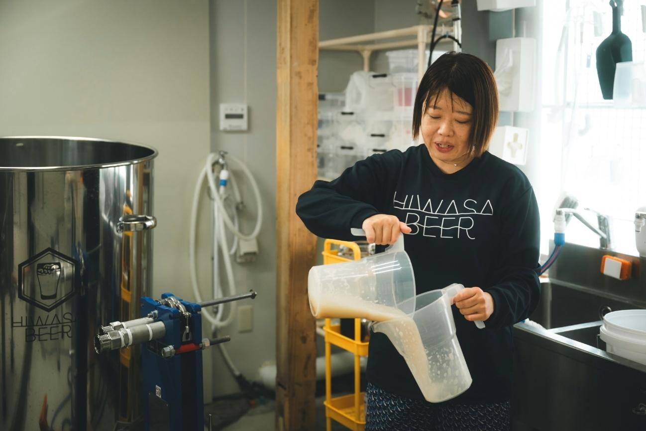 ビールの泡を消すために両手の入れ物に交互にビールを入れる熊谷さん