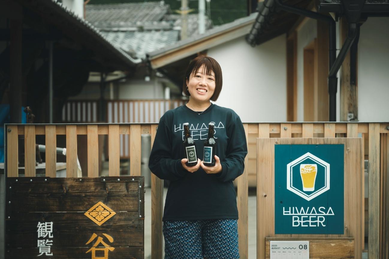 「谷屋」前で「日和佐ビール」を持つ「日和佐ビール」代表・熊谷さん