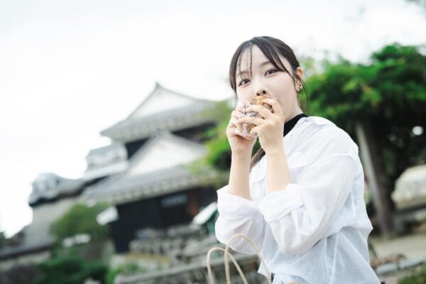 松山城でベーグルを食べる女性