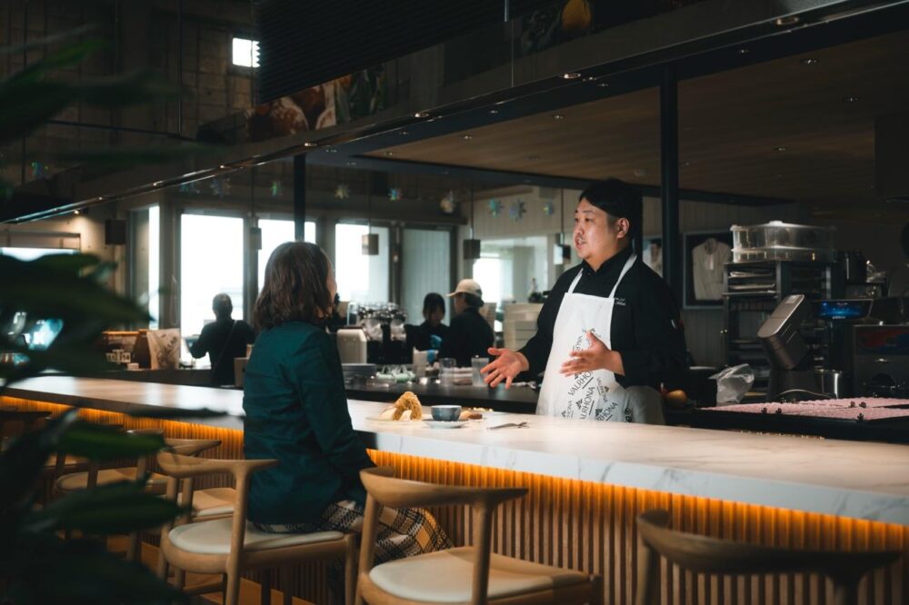 PRISM LAB店内でスイーツの説明をするパティシエ・柴田さん