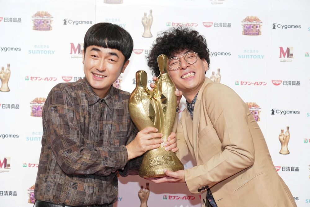 M-1グランプリのトロフィーを持つたくろうのきむらバンドさんと赤木裕さん