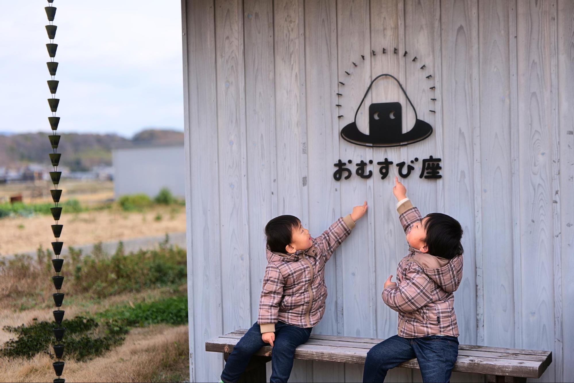 三豊市にある「おむすび座」の看板を指す、さぬきよファミリーのおーちゃんとたーちゃん